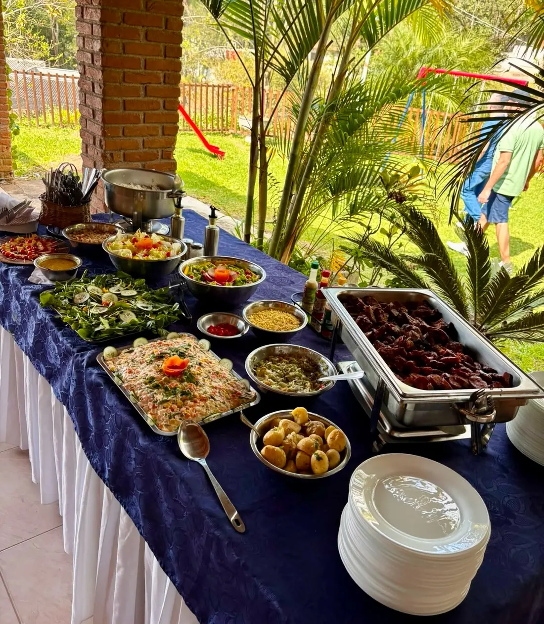 Mesa de buffet ao ar livre com carnes, saladas e guarnições