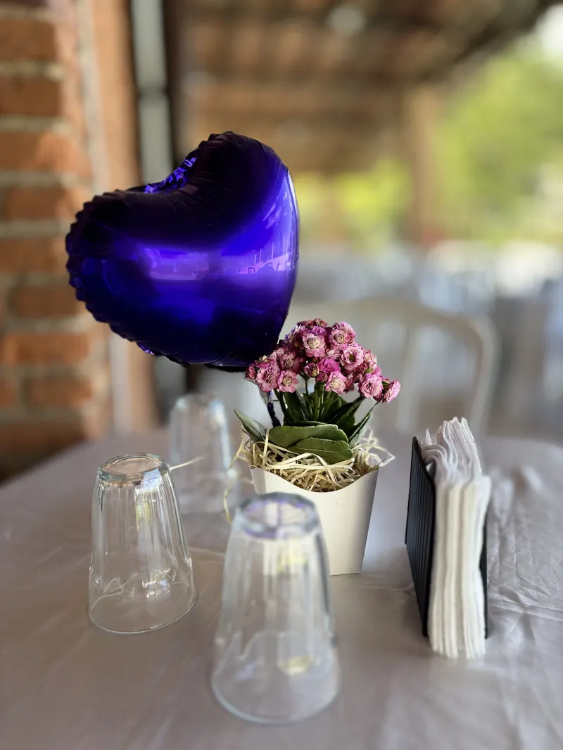 Balão de coração azul e arranjo de flores rosa sobre a mesa dos convidados
