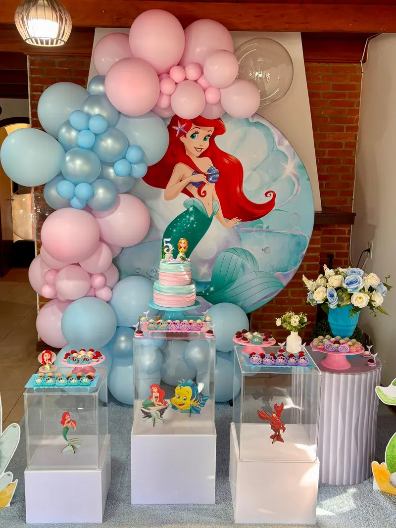 Festa infantil da Pequena Sereia, com painel redondo, balões rosa e azuis e mesa de doces