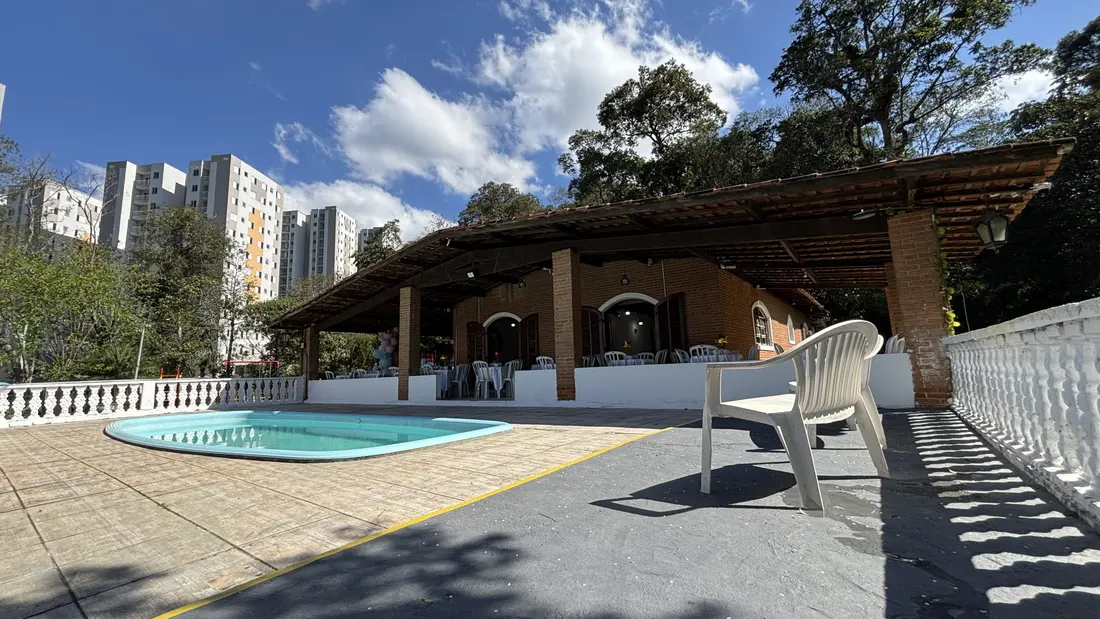 Piscina com deck e espreguiçadeira, ao lado da área coberta, sob céu azul